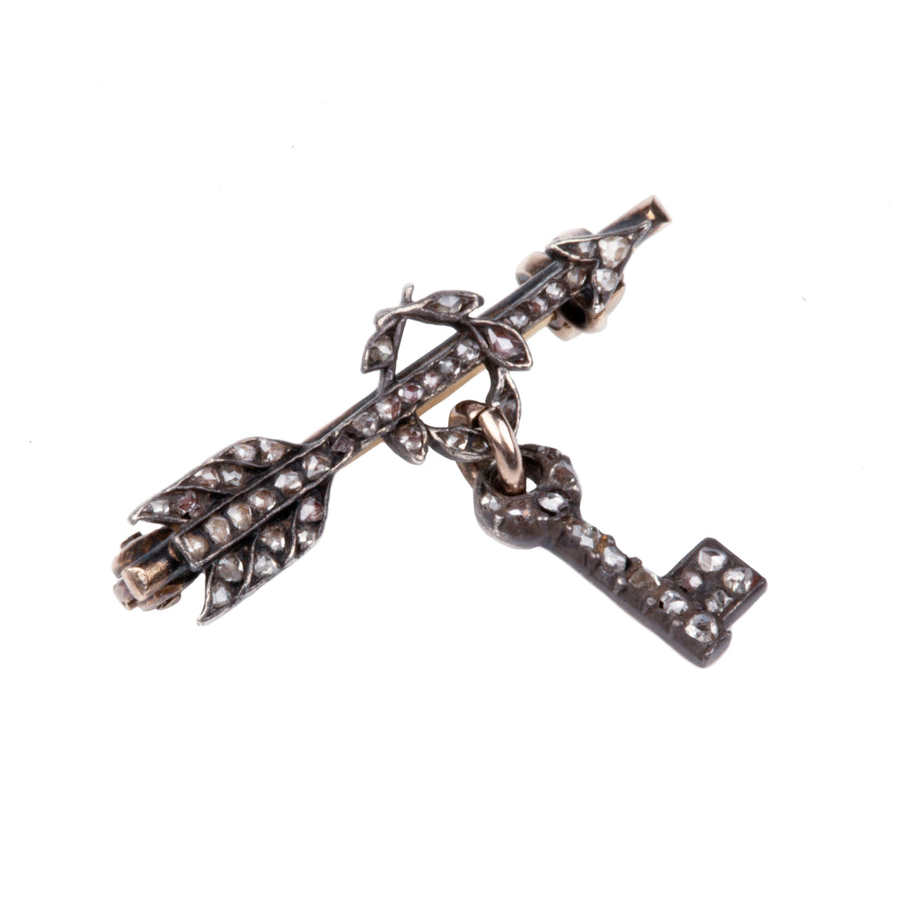 Tiny Victorian era Rose cut diamond arrow brooch with the tiniest key hanging from a laurel wreath. Silver topped gold with original clasp fixture. English in Origin. Circa 1860. Close-up view. 